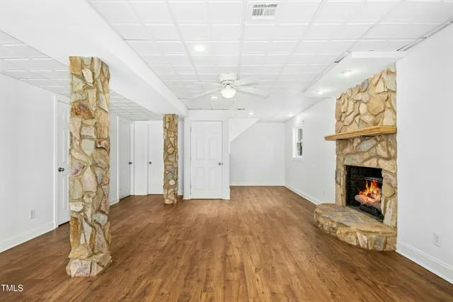 a view of an empty room with wooden floor and a fireplace