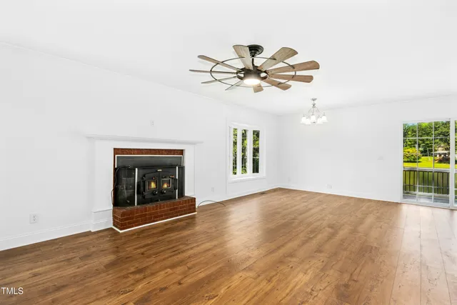 an empty room with wooden floor a ceiling fan and fireplace