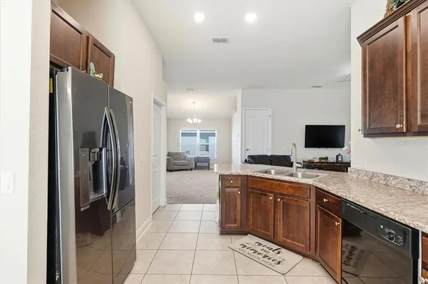 a large kitchen with a large counter top a sink stainless steel appliances and cabinets