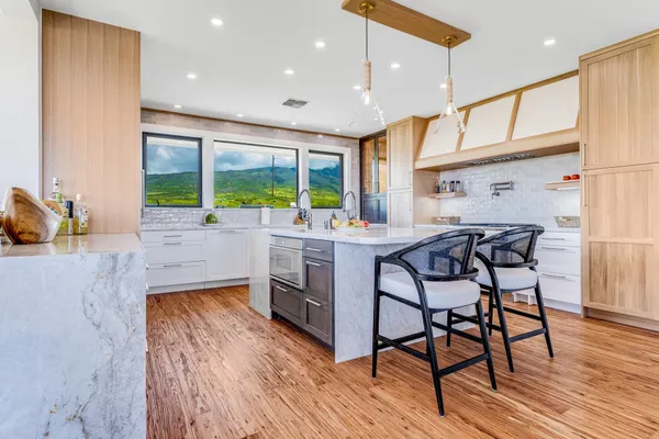 a kitchen with stainless steel appliances kitchen island granite countertop a stove a sink and a dining table with white cabinets