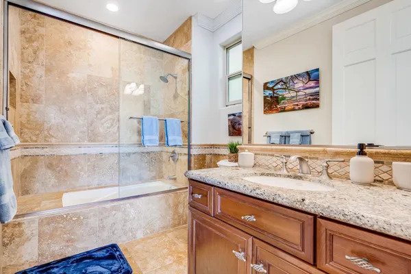 a bathroom with a granite countertop sink a mirror and a shower