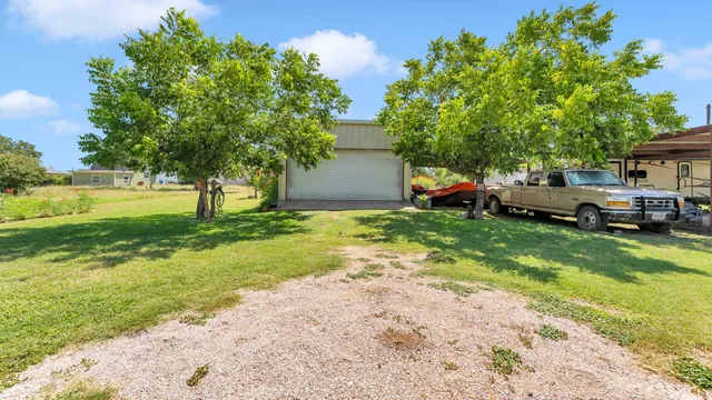 a view of a house with a big yard and large trees