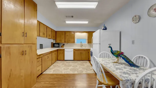 a kitchen with stainless steel appliances granite countertop a sink dishwasher stove refrigerator and couches with wooden floor