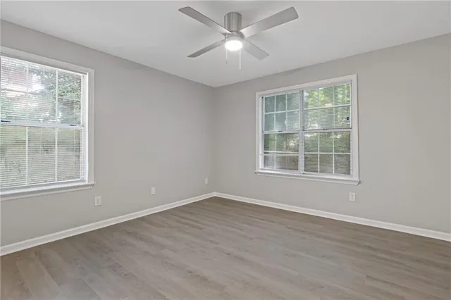 a view of an empty room with wooden floor and a window