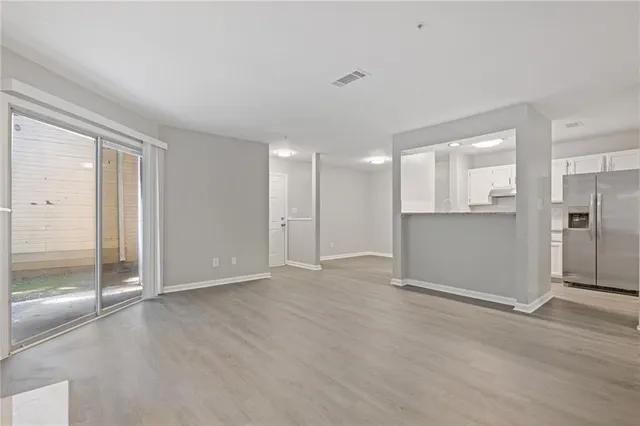 a view of a kitchen with refrigerator and wooden floor