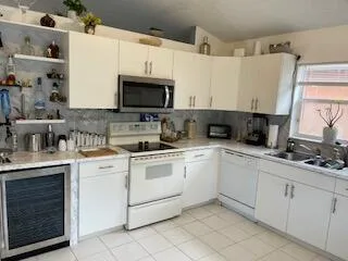 a kitchen with granite countertop a sink stainless steel appliances and white cabinets