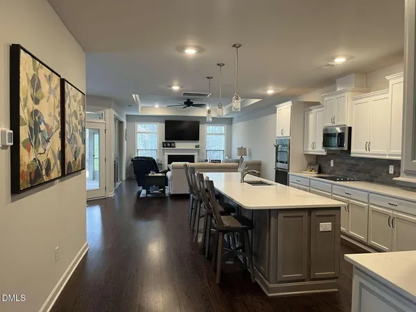 a kitchen with stainless steel appliances granite countertop a stove top oven a sink dishwasher a dining table and chairs with wooden floor
