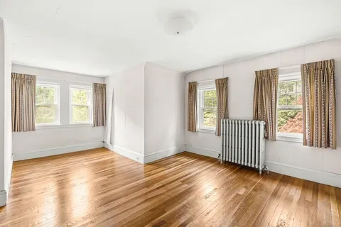 a view of a hallway with wooden floor and a bathroom