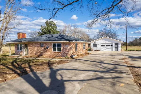 a front view of house with yard and trees in the background