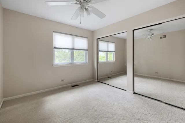 an empty room with chandelier fan and windows