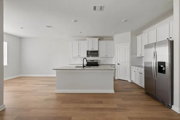 a kitchen with stainless steel appliances granite countertop a refrigerator sink and white cabinets