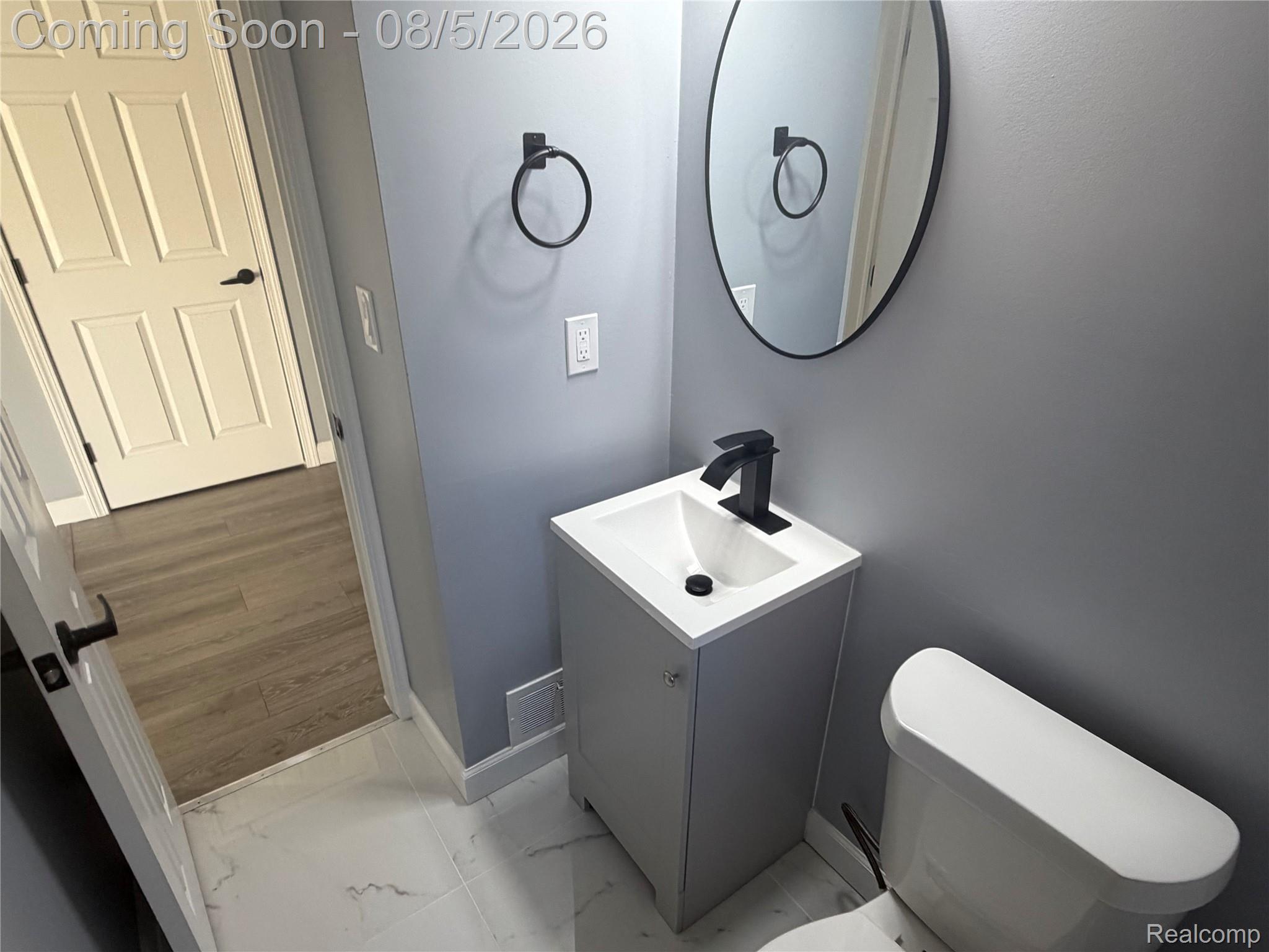 20698 Coachwood Road Riverview, MI 48193 - Photo 10 of 37 Powder room featuring a single vanity with storage, matte black hardware, oval mirror, and white tile flooring