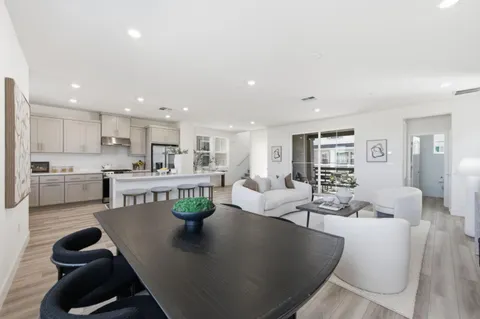 a living room with stainless steel appliances furniture a dining table and kitchen view