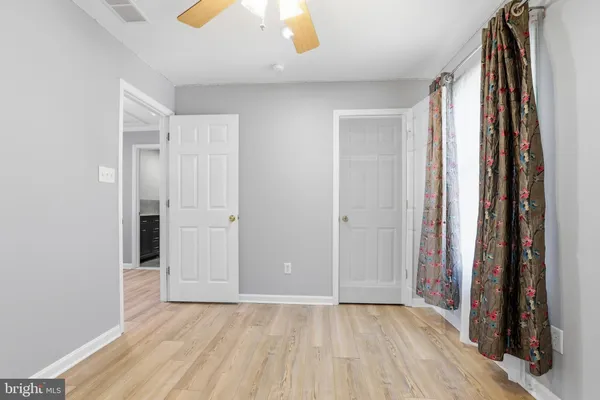 a view of an empty room with closet and wooden floor