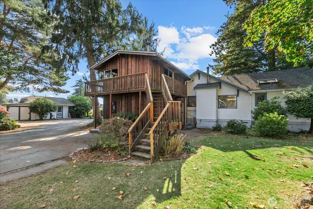 a view of a house with a yard and large tree