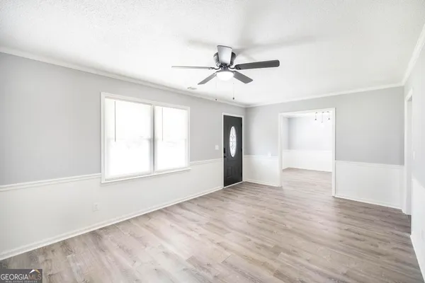 a view of empty room with wooden floor and fan