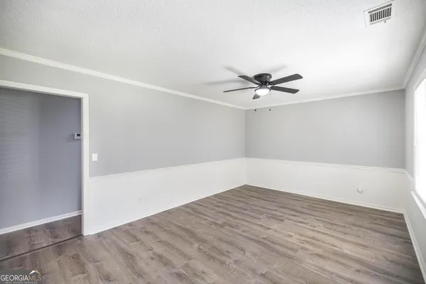 an empty room with wooden floor and ceiling fan