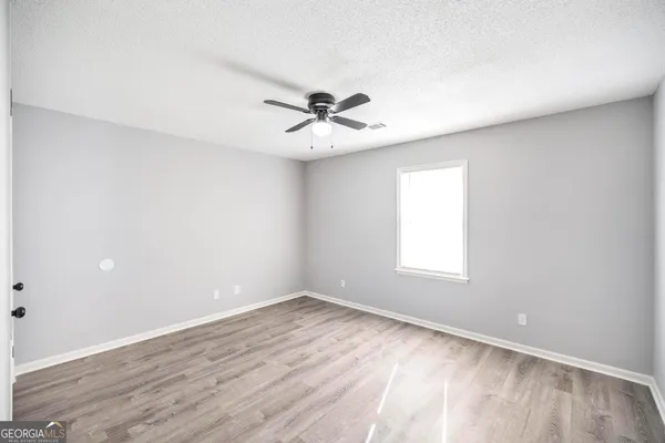 an empty room with wooden floor and ceiling fan
