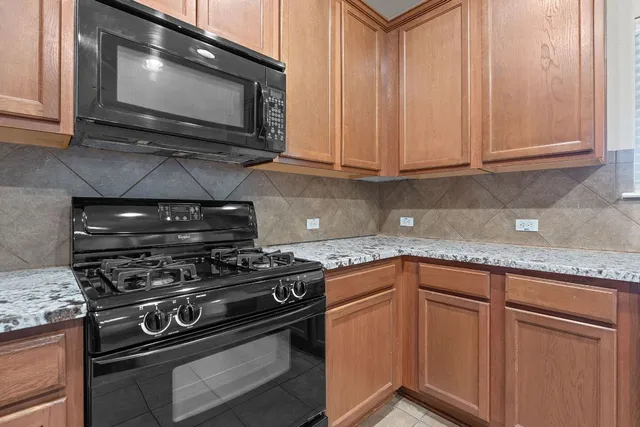 a kitchen with granite countertop a stove top oven microwave and cabinets