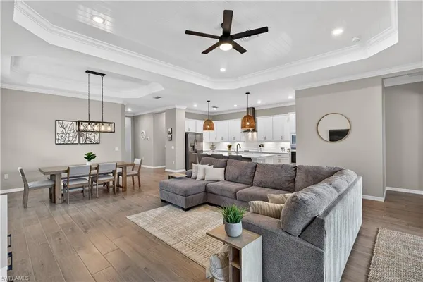 a living room with furniture kitchen view and a wooden floor