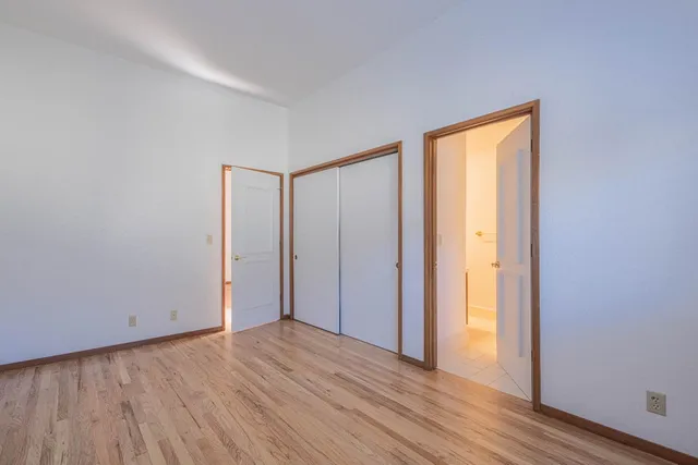 a view of an empty room with wooden floor and closet