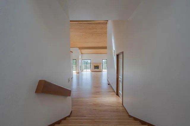 a view of a hallway with wooden floor and a cabinet
