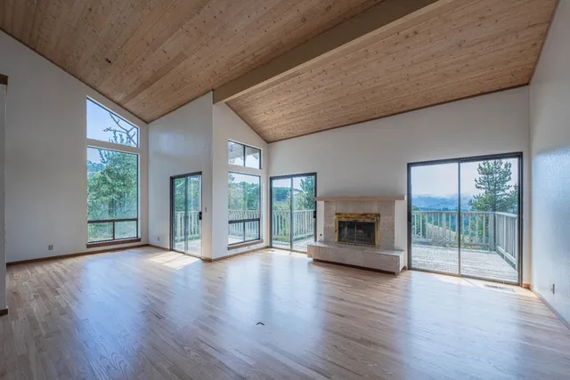 a view of an empty room with wooden floor and a fireplace