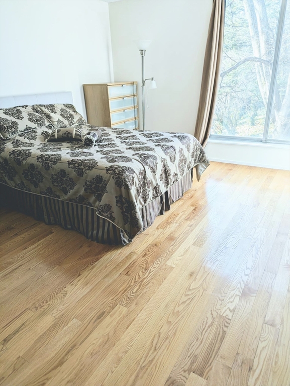 99 Pond Avenue, Unit 409 Brookline, MA 02445 - Photo 12 of 28 a bedroom with a bed and wooden floor