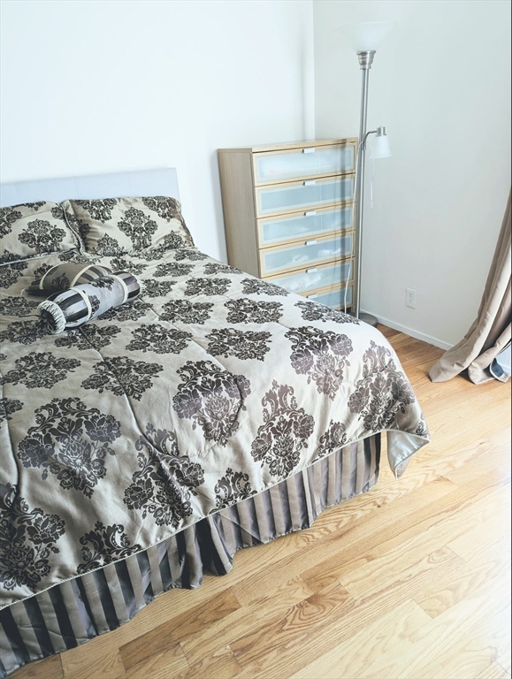 99 Pond Avenue, Unit 409 Brookline, MA 02445 - Photo 14 of 28 a bedroom with a bed and wooden floor