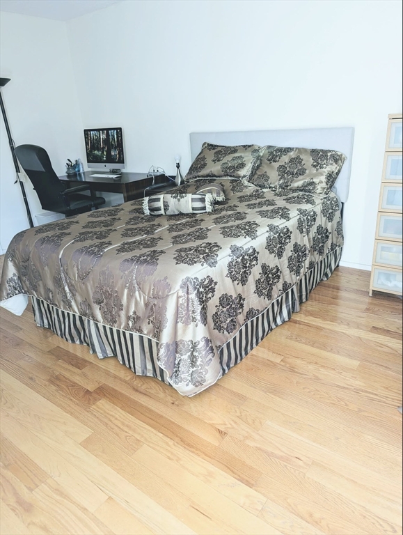 99 Pond Avenue, Unit 409 Brookline, MA 02445 - Photo 17 of 28 a bed sitting in a bedroom next to a white bed and a wooden floor