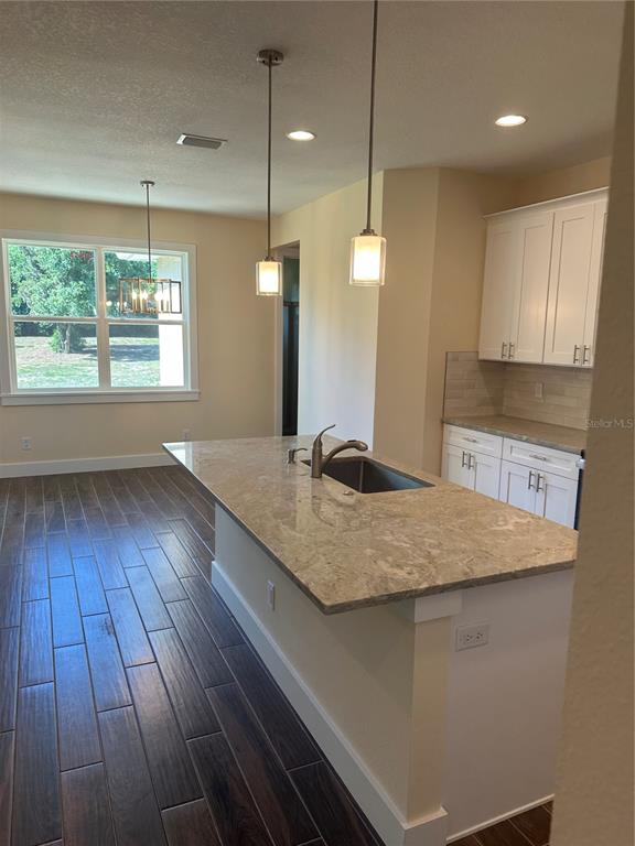 4011 Amber Road Valrico, FL 33594 - Photo 30 of 32 a kitchen with kitchen island granite countertop wooden floors wooden cabinets a sink and a window