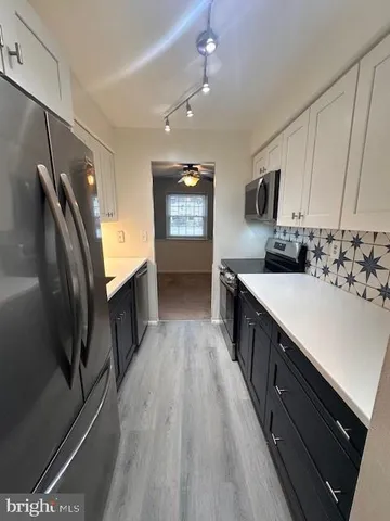 a large kitchen with stainless steel appliances a sink window and wooden floor