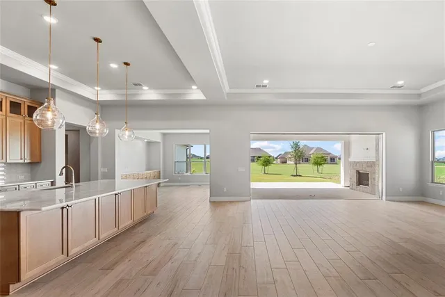 a large kitchen with stainless steel appliances a large window a oven and a sink with wooden floors