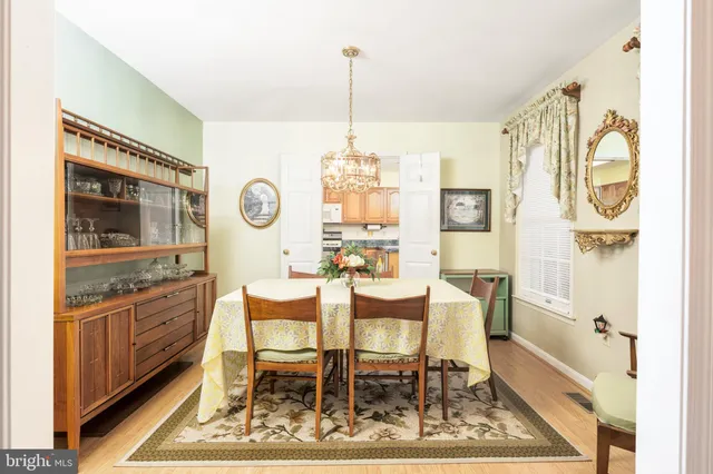 a dining room with chandelier and wooden floor