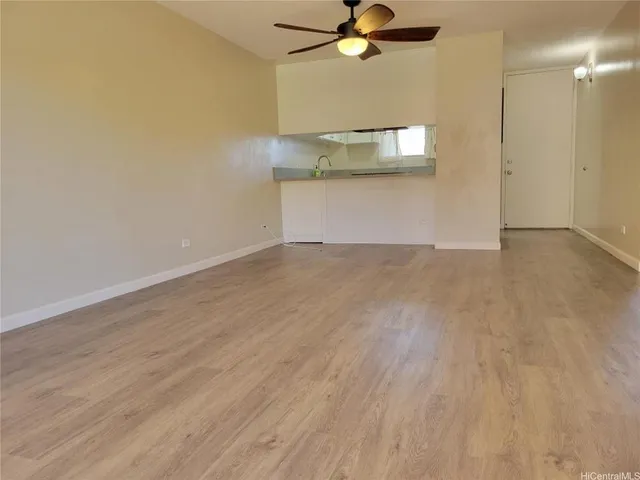 an empty room with a chandelier fan and wooden floor