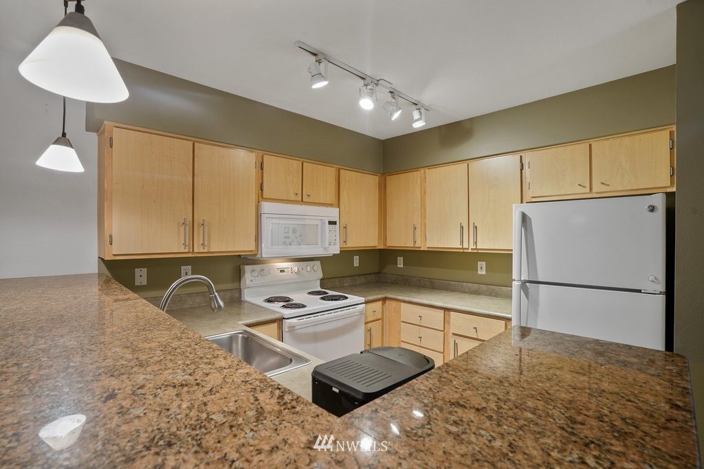 10709 Valley View Road, Unit A105 Bothell, WA 98011 - Photo 12 of 26 a kitchen with a refrigerator a stove a sink cabinets and a counter top space