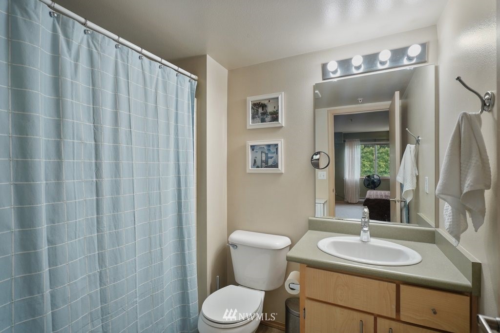 10709 Valley View Road, Unit A105 Bothell, WA 98011 - Photo 19 of 26 a bathroom with a toilet a sink and a mirror