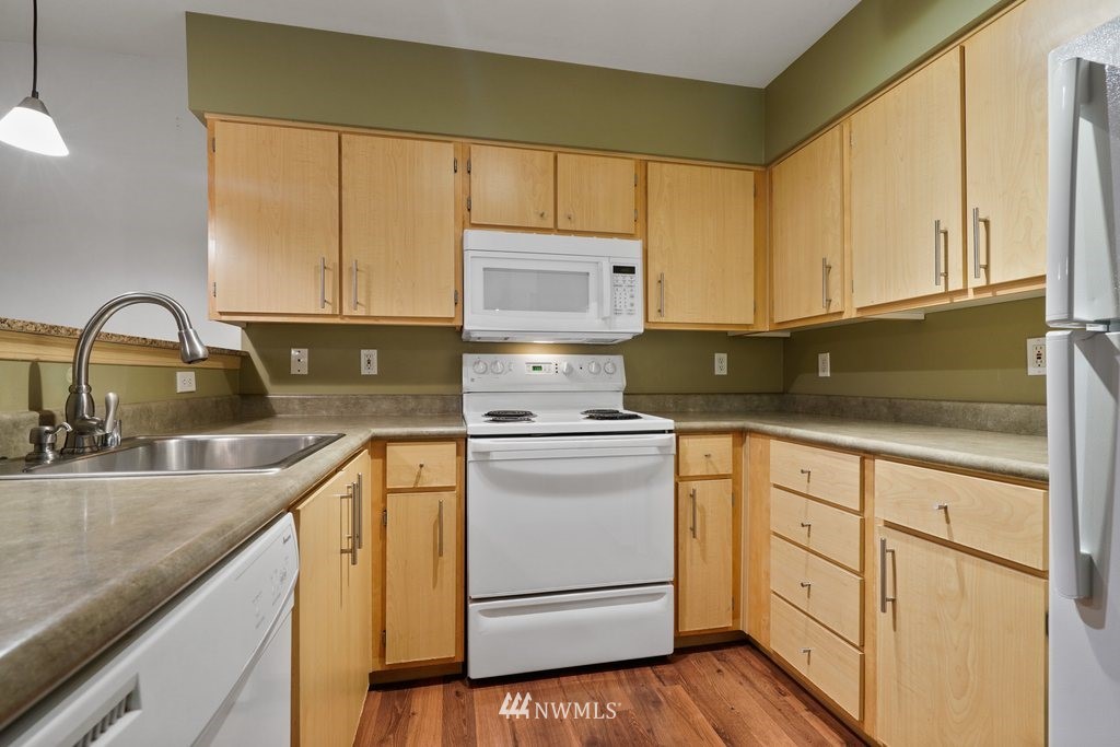 10709 Valley View Road, Unit A105 Bothell, WA 98011 - Photo 9 of 26 a kitchen with granite countertop white cabinets and white appliances