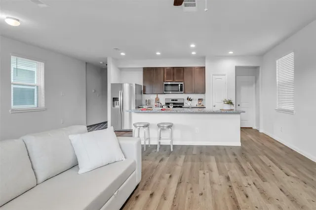 a living room with stainless steel appliances kitchen island granite countertop wooden floor a couch and a window