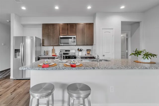 a kitchen with stainless steel appliances granite countertop a sink a stove a refrigerator and a refrigerator