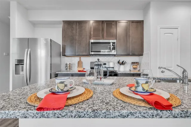 a kitchen with stainless steel appliances granite countertop a sink refrigerator and stove