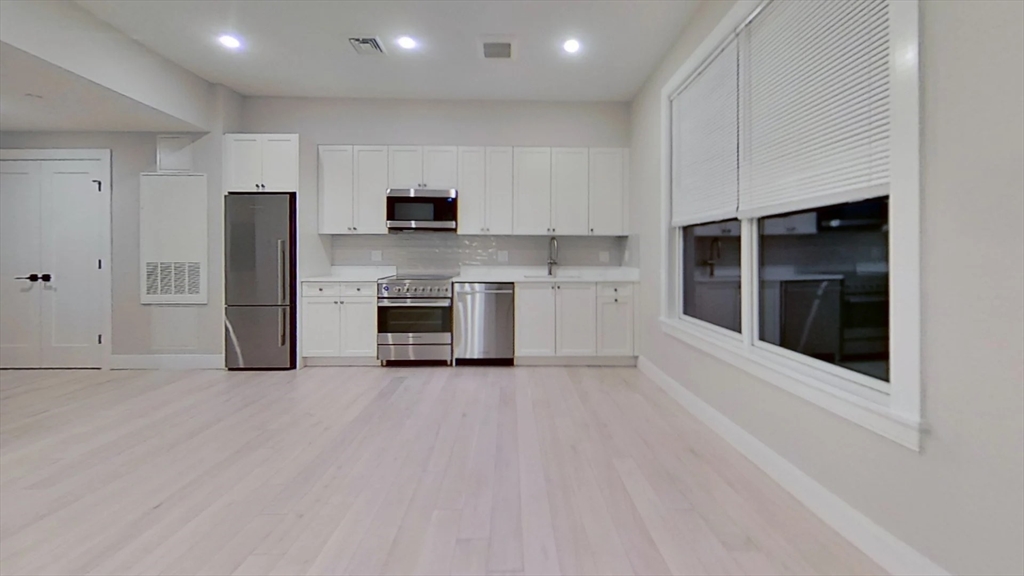197 Green Street, Unit 207 Boston, MA 02130 - Photo 2 of 4 a view of kitchen with stainless steel appliances granite countertop a stove top oven and refrigerator