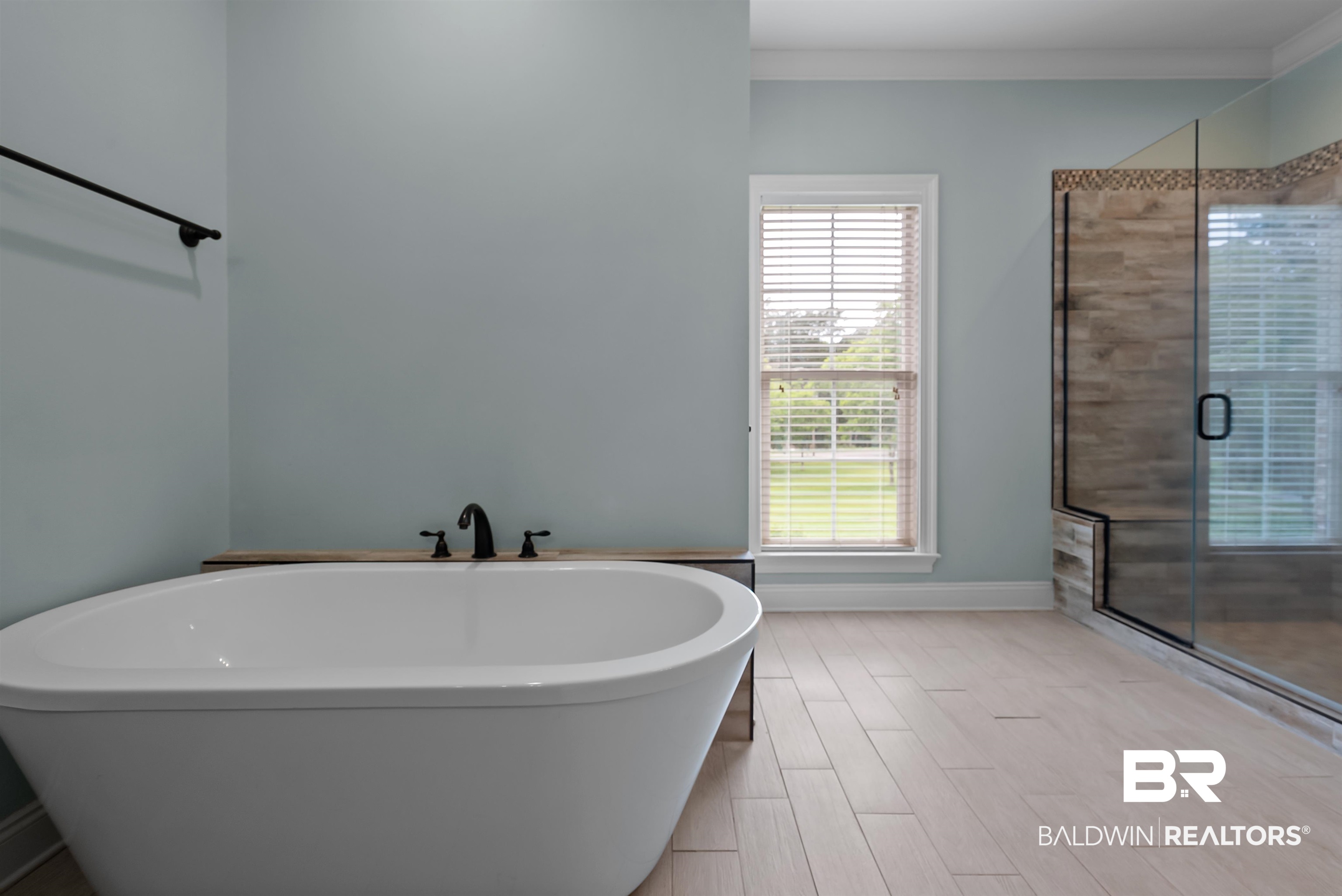 12070 Comalander Road Fairhope, AL 36532 - Photo 24 of 50 Freestanding oval soaking tub with matte black fixtures, set on wood-finish plank tile flooring