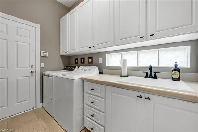 a kitchen with white cabinets and sink