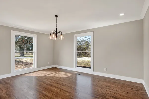 a view of an empty room with wooden floor and a ceiling fan