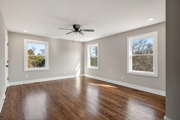 a view of an empty room with wooden floor and windows