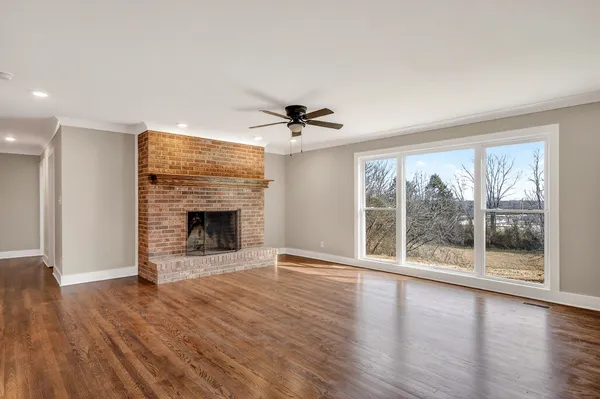 a view of an empty room with a window and wooden floor