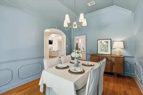 a dining room with wooden floor a chandelier fan a wooden table and chairs