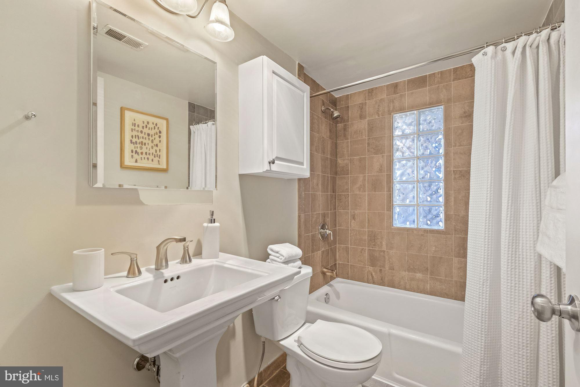 1701 16th Street Northwest, Unit 316 Washington, DC 20009 - Photo 31 of 42 Travertine bath w/shower/tub & a pedestal sink