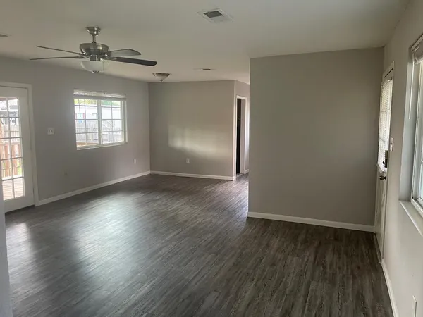 an empty room with wooden floor and windows